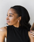 Woman wearing reflective rose gold mirror acrylic earring and black sleeveless top  with a neutral background.