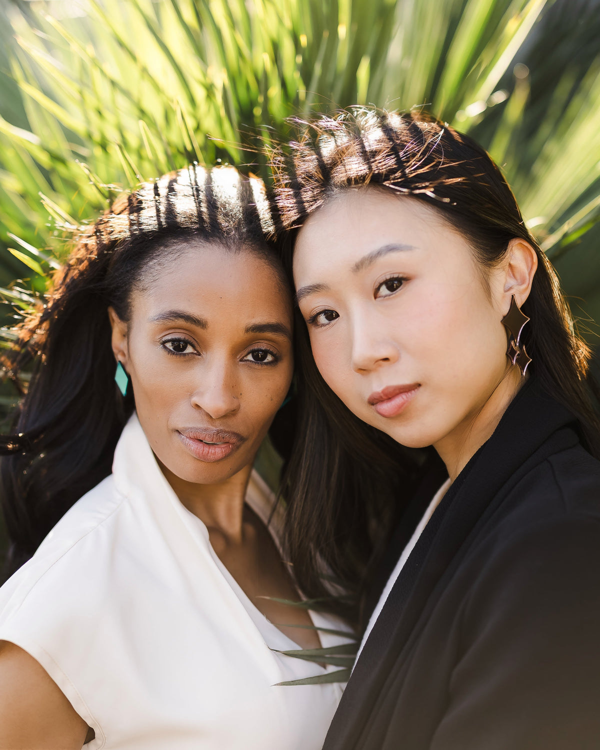 Two women outside wearing minimalist statement earrings.